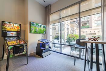 A room with a pinball machine and a tv showing a game